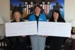 three women holding two oversized checks