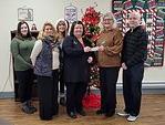 6 people with check donation standing in front of Christmas tree